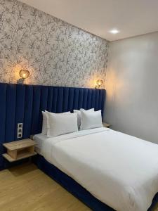 Maarif Elite Suites في الدار البيضاء: غرفة نوم مع سرير كبير مع اللوح الأمامي الأزرق