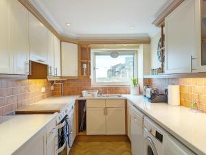 a kitchen with white cabinets and a window at The Gables in Bognor Regis