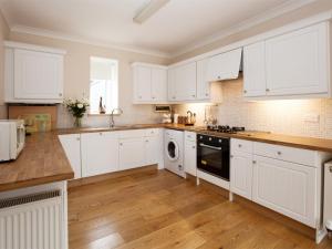 2 Bed in Howden G0113 في Saltmarshe: مطبخ أبيض مع أرضيات خشبية ودواليب بيضاء