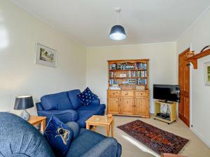 sala de estar con sofá azul y TV en 2 bed in Strontian CA046, en Scotstown