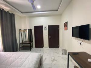 a bedroom with a bed and a flat screen tv at Post Ridge Hotel in Accra