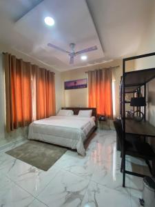a bedroom with a bed and orange curtains at Post Ridge Hotel in Accra