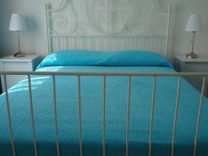 a bed with a blue bedsheet and two night stands at Appartamenti Condominio Daniele in Grado
