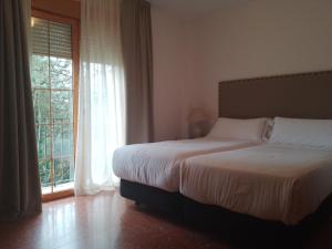 - une chambre avec un lit et une grande fenêtre dans l'établissement Hotel Tugasa El Almendral, à Setenil de las Bodegas