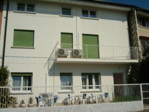 a white building with chairs and tables on a balcony at Appartamenti Condominio Daniele in Grado