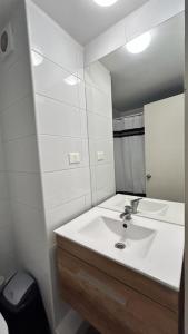 y baño con lavabo blanco y espejo. en Depto nuevo en republica cercano al movistar arena en Santiago