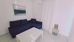 een woonkamer met een blauwe bank en een tafel bij STAY Elysian House in Limassol
