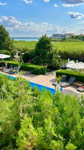 - une vue sur la piscine bordée d'arbres et l'océan dans l'établissement Pensiunea Alfa, à Mamaia Nord – Năvodari