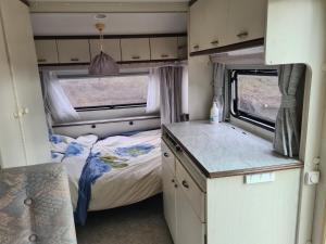 Habitación pequeña con cama y cocina en una cabaña en Geweldige caravan op een off-grid locatie, en Santo Tomé