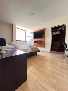 a bedroom with a bed and a desk and a tv at Torre Isos in Cochabamba