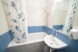 baño azul y blanco con lavabo y bañera en Comfort 28 B, en Miskolc