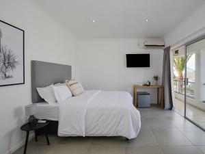 a white bedroom with a bed and a television at 19 Beach Road in Cape Town