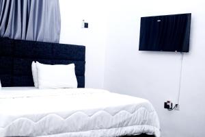 a bedroom with a white bed with a black headboard at Coded Hub Guest House in Lekki