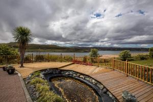 una terraza de madera con un estanque y una palmera en Loch Eyre Oasis en Kensaleyre