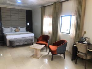 a bedroom with a bed and two chairs and a table at Roban Hotels Limited in Enugu