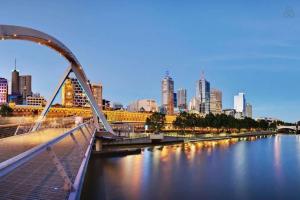 a bridge over a river with a city in the background at A Chic 2BR Apt Right Next to Melbourne Central in Melbourne