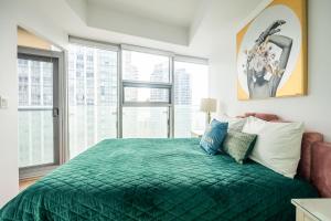 a bedroom with a green bed with large windows at GLOBALSTAY. Amazing Downtown Apartments in Toronto