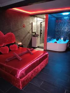 a red bed in a room with a tub at L'instant romance Le Romantique in Castelnaudary