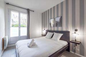 een slaapkamer met een groot wit bed en een raam bij City Center by Plaza - Proche Disneyland Paris in Chessy