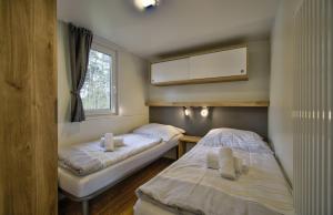 two beds in a small room with a window at Camping-und Ferienpark Havelberge in Groß Quassow