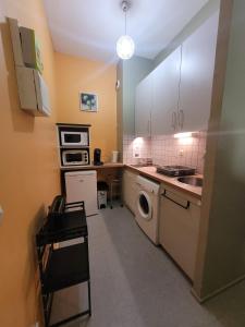 a kitchen with white cabinets and a washer and dryer at Studio Rez de Chaussée Meublé in La Roche-Posay