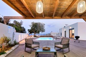 a patio with a pool and chairs and a table at Villa Emilia - with private swimming pool in Agia Pelagia