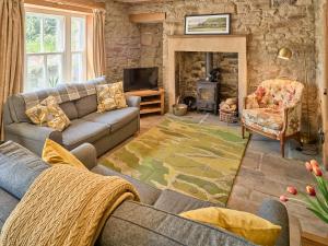 a living room with a couch and a fireplace at Bridge End in Langthwaite