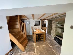 a dining room with a table and a stone wall at Bridge End in Langthwaite