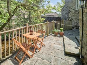 a wooden table and two chairs on a patio at Bridge End in Langthwaite