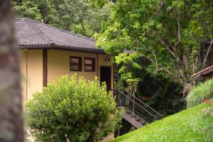 une maison jaune avec un escalier menant à elle dans l'établissement Pousada Terra Crua, à Visconde de Mauá