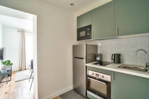 cocina con nevera de acero inoxidable y fregadero en Splendid apartment for 2 people, en Aubervilliers