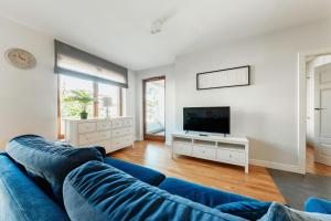 ein Wohnzimmer mit einem blauen Sofa und einem TV in der Unterkunft Apartament Premium Plac Litewski 7 in Lublin