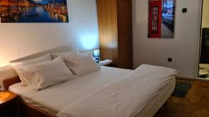 Schlafzimmer mit einem Bett mit weißer Bettwäsche und Kissen in der Unterkunft De LUX Apartman in Čačak