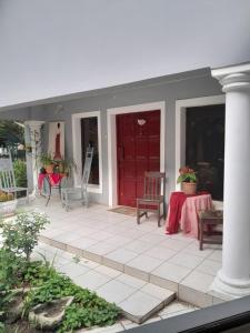 a porch with a red door and a table and chairs at Ebenezer Self Catering in Groblersdal