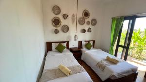 two beds in a room with a window at La village hills view in Nusa Penida