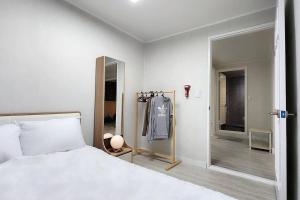 1 dormitorio con cama blanca y espejo en The Hari House, en Seúl