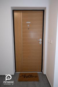een houten deur in een kamer met een mat ervoor bij Petković apartmani STUDIO32 in Jagodina