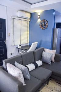 a living room with a couch and a clock on the wall at The Grenadines Apartment in Lagos