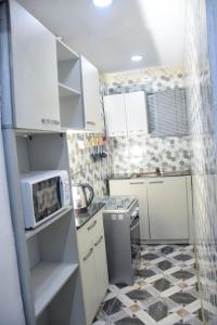 a small kitchen with white cabinets and a microwave at The Grenadines Apartment in Lagos