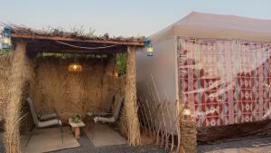 une tente avec 2 chaises et une table. dans l'établissement مخيم يمك دروبي, à Al-Ula