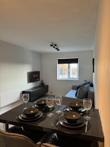 a dining room table with plates and wine glasses at Apartment Close to the Studios in Borehamwood