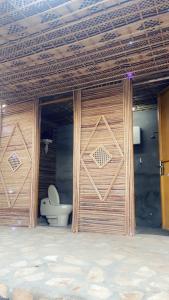 łazienka z toaletą i drewnianymi drzwiami w obiekcie مخيم يمك دروبي w mieście Al-Ula