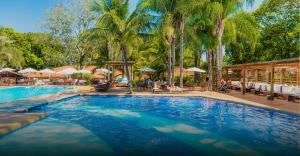 una gran piscina con palmeras en un complejo en Santa Clara Eco Resort, en Dourado