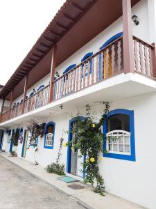 a white building with blue windows and a balcony at Pousada Flores da Terra in Paraty