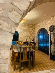 una sala da pranzo con tavolo e parete in pietra di Villa Maison des Arts - Oasis de Calme et Tranquillité Près de l'Aéroport d'Essaouira a Essaouira