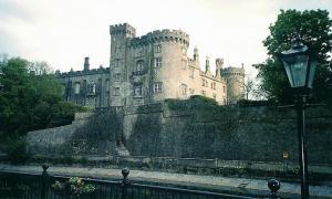 a castle with a wall and a street light at The Waterfront Townhouse Accommodation in Kilkenny