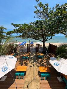 uma praia com mesas e guarda-sóis e uma árvore em Santorini Beach Hotel em Arraial d'Ajuda