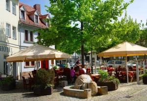 um grupo de pessoas sentadas em mesas sob guarda-chuvas em Zur Alten Schmiede em Naumburg