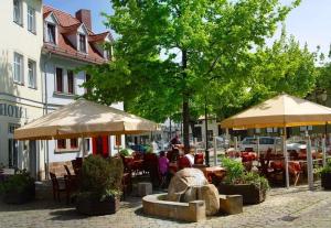 eine Gruppe von Personen, die unter Sonnenschirmen an Tischen sitzen in der Unterkunft Zur Alten Schmiede in Naumburg