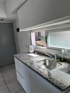 um balcão de cozinha com um lavatório e uma janela em Dos ambientes San Justo em San Justo